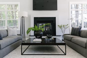 A modern living room with a grey sofa, a black coffee table, and a fireplace.